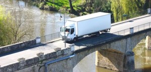 truck passing a stone old bridge